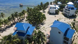 Ein Resort mit mehreren Gebäuden, einem Strand und einem Steg.