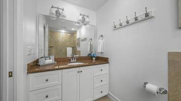 A bathroom with a large mirror, white cabinets, a sink, and a towel rack.