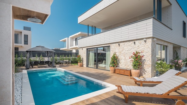 A modern house with a swimming pool, outdoor furniture, and potted plants. - Luxury Villa Moonstone with Pool (Funtana)