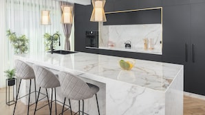 A modern kitchen with a marble countertop, black cabinets, and pendant lights. - Luxury Villa Moonstone with Pool (Funtana)