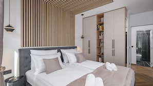 A modern bedroom with a large bed, a wooden slatted ceiling, a wardrobe, and a bathroom visible through an open door. - Luxury Villa Moonstone with Pool (Funtana)