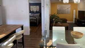 A modern living room with a glass dining table, a sofa, a TV, and a plant. - The Bachelor (Mirabel)