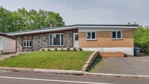 A single-story house with a brick exterior, a front porch, and a well-maintained lawn. - The Bachelor (Mirabel)