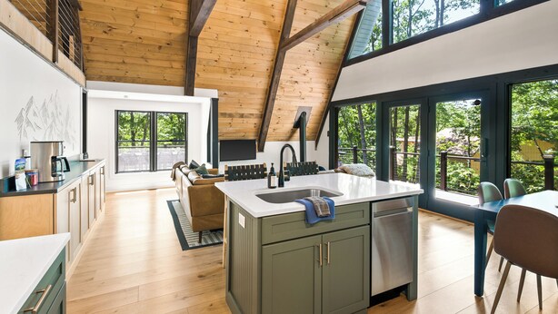 A spacious kitchen with a central island, wooden beams on the ceiling, and large windows offering a view of greenery outside. - 1 mile to Bryce Resort l 4 BR l Hot Tub l Fire Pit l Game Room  (Basye)