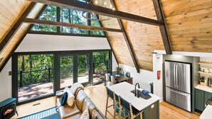 A modern loft with a large wooden ceiling, a dining area, a kitchen with a stainless steel refrigerator, and a cozy seating area with a fireplace. - 1 mile to Bryce Resort l 4 BR l Hot Tub l Fire Pit l Game Room  (Basye)