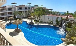 Relax by the pool surrounded by palm trees and a soothing waterfall.