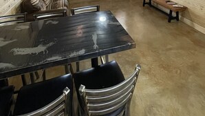 A spacious room with a large black table, several chairs, a bench, a television mounted on the wall, and a door with a window. - Country Cabin with Jacuzzi Tub and Meramec River Access and Pets welcome! (Bourbon)