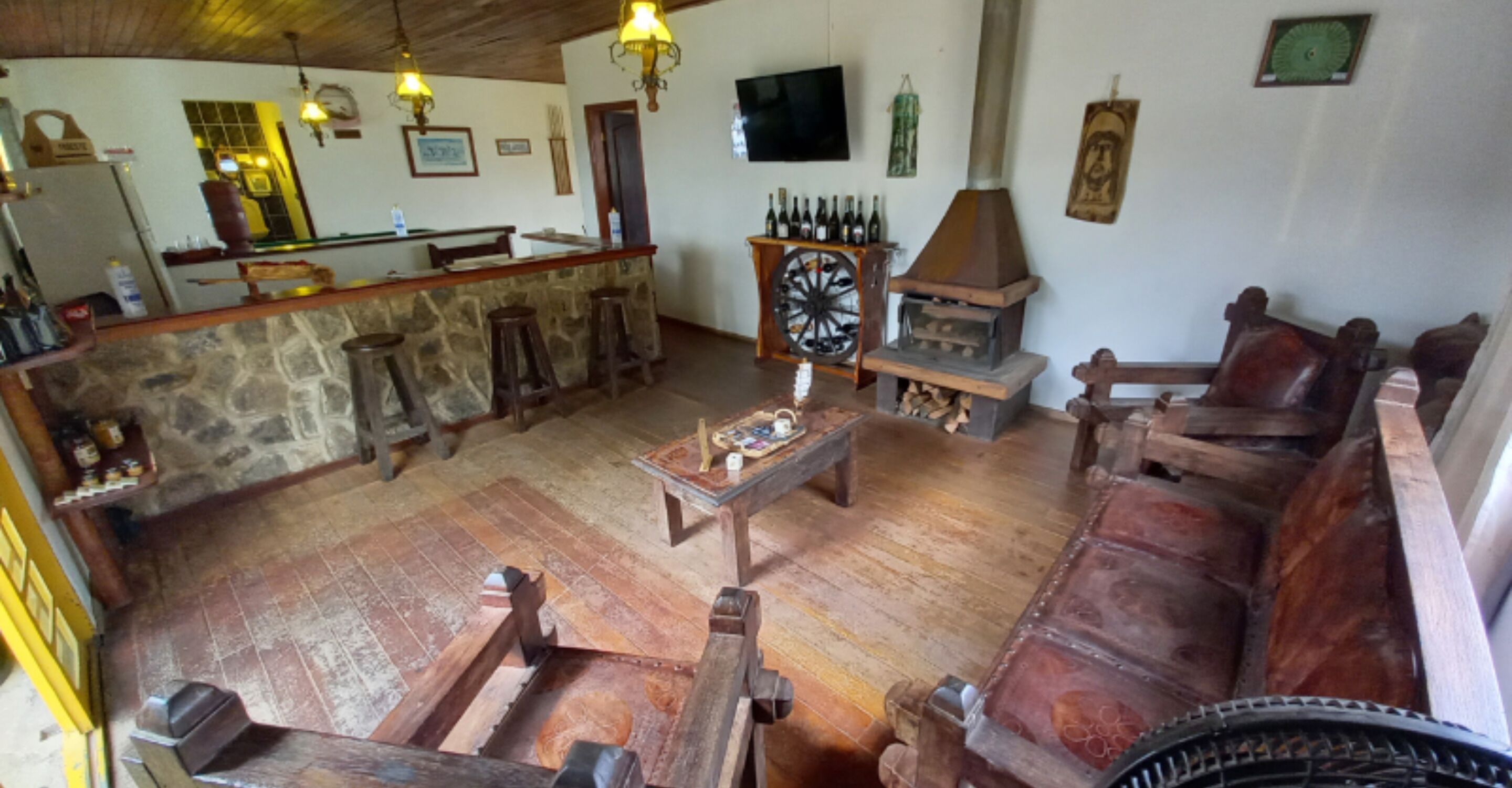 A rustic interior with a stone bar, wooden furniture, and a traditional wood stove.