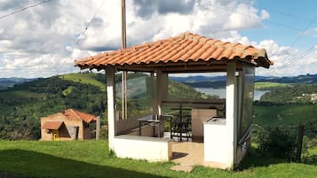 A small, rustic gazebo with a tiled roof overlooking a lush valley.
