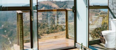 A modern room with large glass windows offering a view of a hilly landscape.