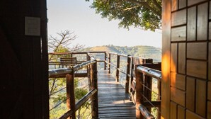 A wooden bridge leading to a scenic overlook with a view of hills and trees. - Pousada do Xerife (Caconde)