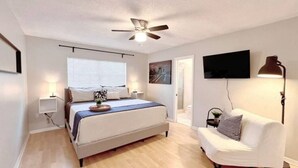 A bedroom with a bed, bedside tables, a ceiling fan, a TV, and a lamp.