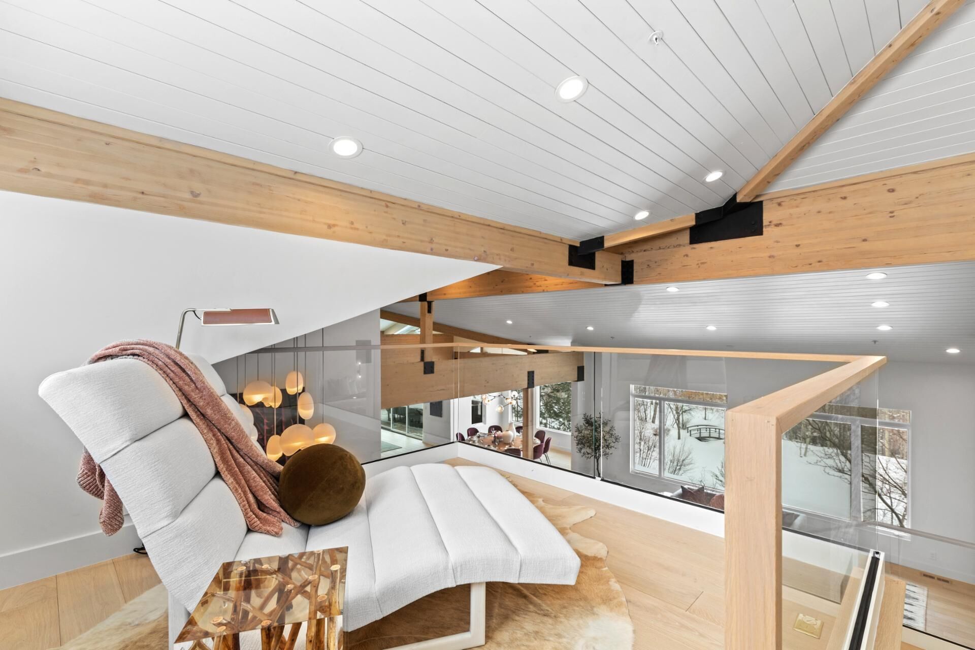 Un interior moderno con un sofá blanco, una mesa de vidrio y vistas al exterior.