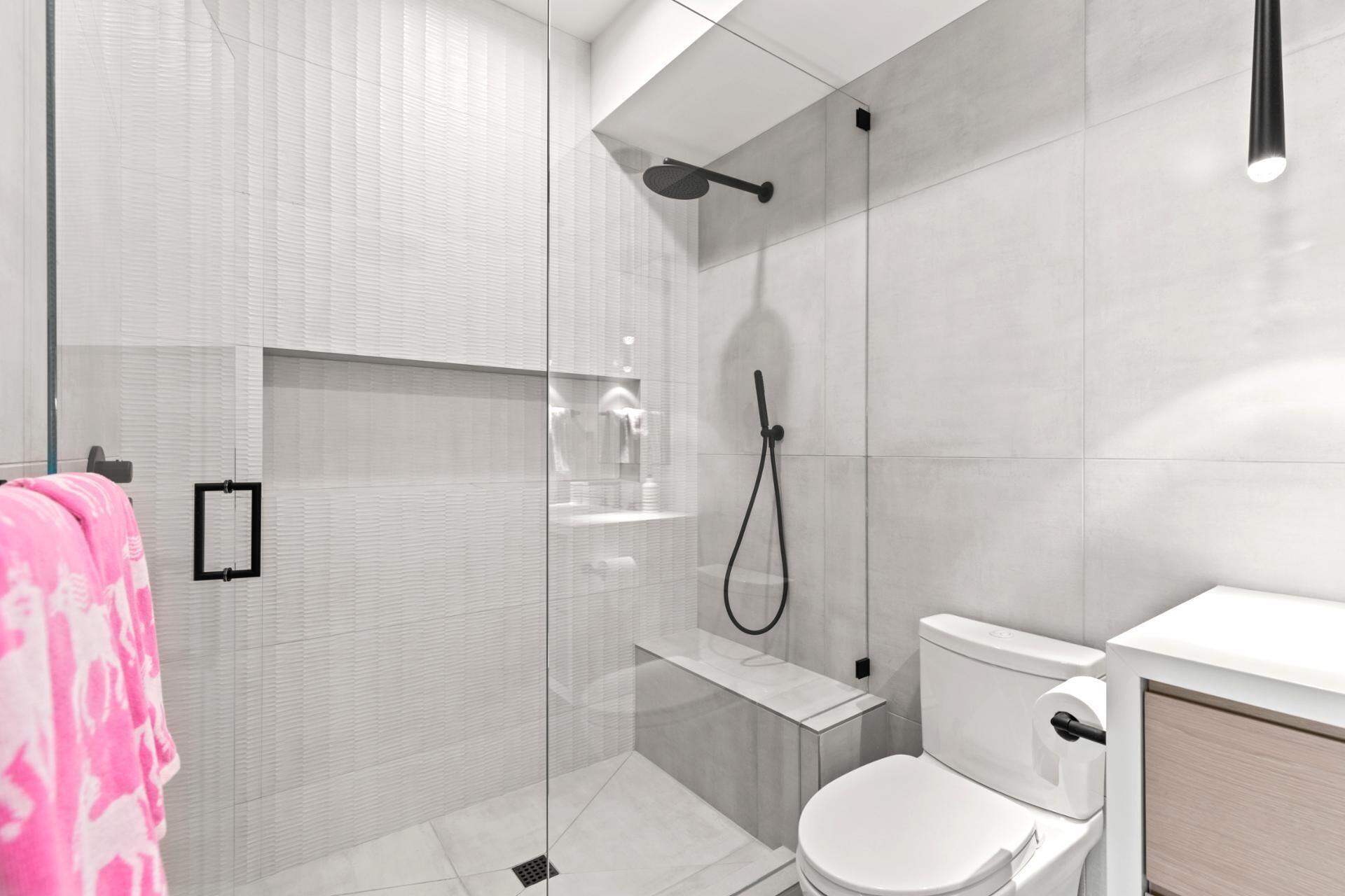 Un baño moderno con cabina de ducha de vidrio, inodoro y lavamanos.
