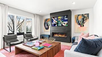 A modern living room with a fireplace, a television, and artwork on the walls.