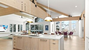 Una cocina moderna con una isla central, ventanas amplias y un comedor con sillas moradas.