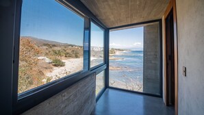 A modern interior with large windows offering a view of a beach and ocean. - Ocean front house Punta de Mita (Punta de Mita)