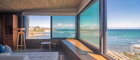 Enjoy a serene ocean view from the large window, with a plush bed and small table nearby.