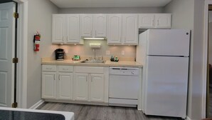 A kitchen with white cabinets, a white refrigerator, a dishwasher, and a coffee maker.