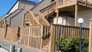 A wooden deck leading to a building with multiple balconies and a staircase.