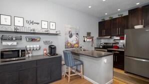 Een moderne keuken met donkere kastjes, een centraal eiland, een magnetron en een koelkast.
