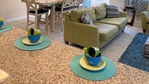 A living room with a sofa, a dining table with chairs, a TV on a stand, and a patterned rug. - Compass Bay by CozyKey (Kissimmee)