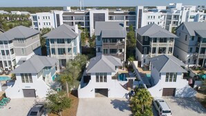 A modern residential complex with multiple two-story buildings, each featuring a balcony and a pool. - Carriage House!  STEPS from Rosemary Tennis Courts! (Inlet Beach)