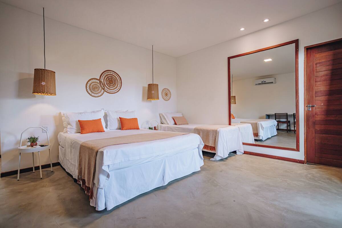 A hotel room with two beds, a large mirror, and a wooden door.