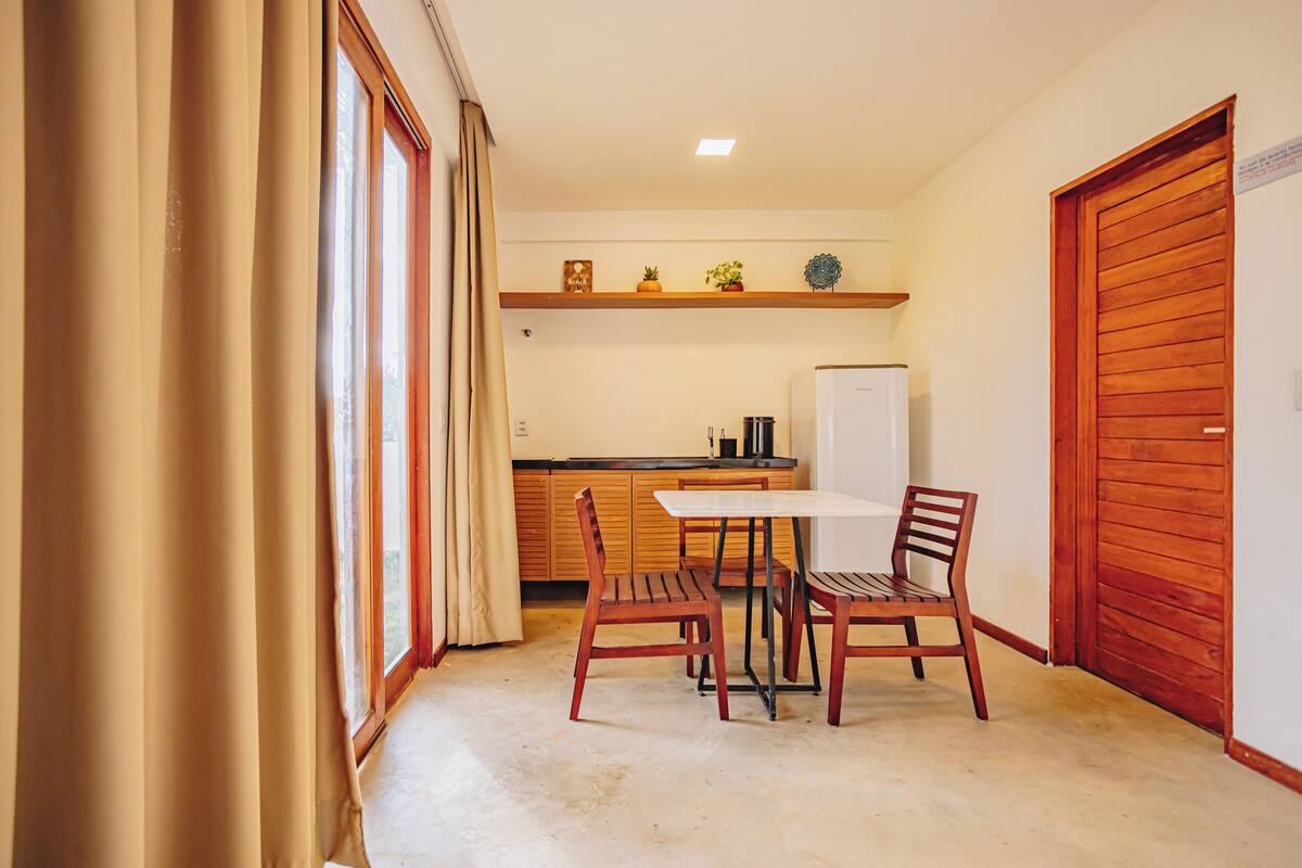 A compact kitchen with a dining table and chairs, wooden cabinets, and a refrigerator.