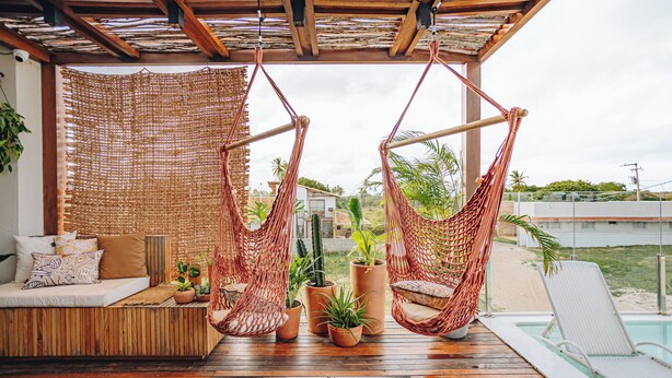 Una terraza de madera con una hamaca, un sofá y plantas en macetas.