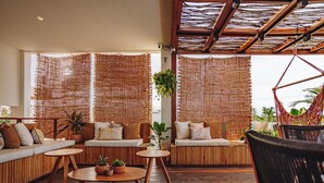 Un espacio al aire libre acogedor con mobiliario de madera y paneles trenzados que ofrecen sombra.