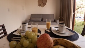 Un ambiente de desayuno con una mesa, un sofá y vistas al exterior.