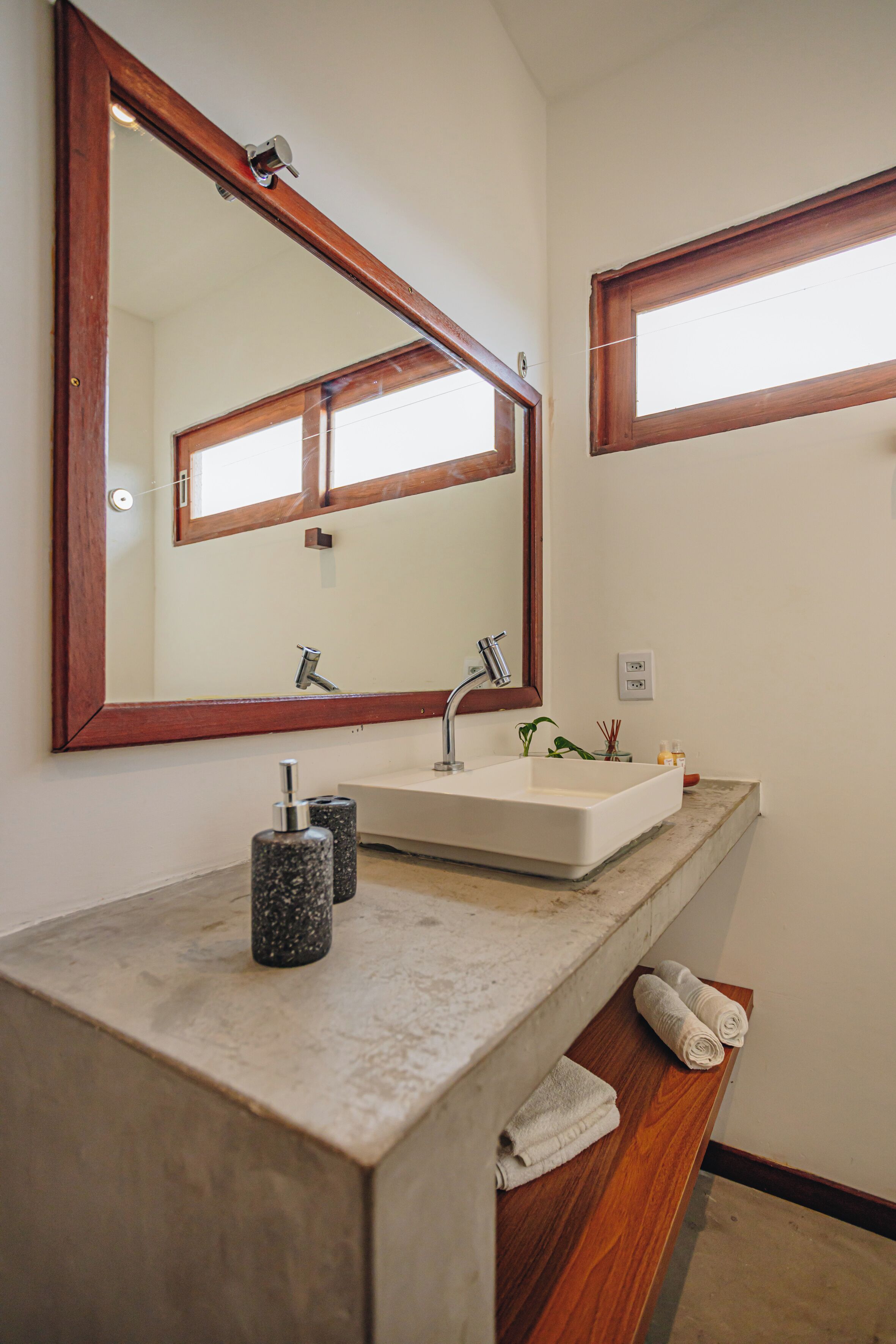 A bathroom with a large mirror, a sink, and a wooden vanity.