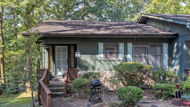 Une maison à deux étages avec un porche à l’avant, un garage et un petit jardin agrémenté d’un barbecue.