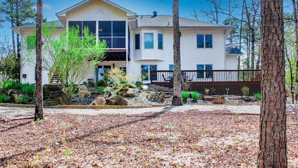A two-story house with a front porch, a covered deck, and a landscaped yard with trees and shrubs. - 18932 - 32 Belleza Way (Hot Springs Village)
