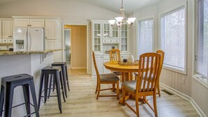 A kitchen with white cabinets, a granite countertop, a central island with stools, and a chandelier. - 18932 - 32 Belleza Way (Hot Springs Village)