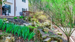A house with a covered patio, a grill, and a stone pathway leading to a wooden deck. - 18932 - 32 Belleza Way (Hot Springs Village)
