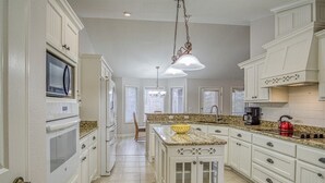 A spacious kitchen with white cabinetry, granite countertops, and a central island. - 18932 - 32 Belleza Way (Hot Springs Village)