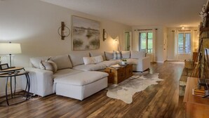 Ein geräumiges Wohnzimmer mit einem Ecksofa, einem Holztisch und einem Kuhfellteppich.