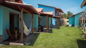 A row of houses with tiled roofs, a grassy yard, and outdoor seating areas. - Pousada Villa Kai  (São Miguel dos Milagres)