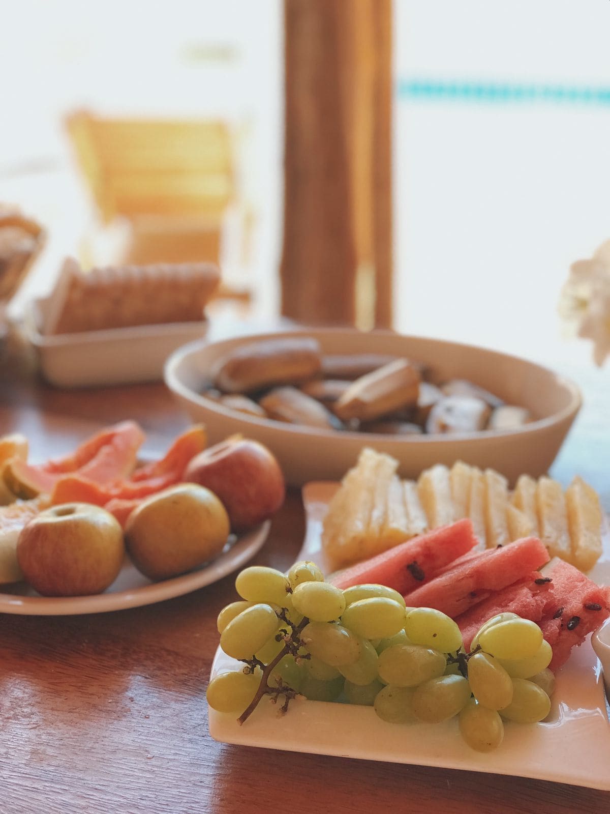 Une table garnie de divers fruits et pâtisseries, notamment des raisins, des pommes et des tranches de pastèque.