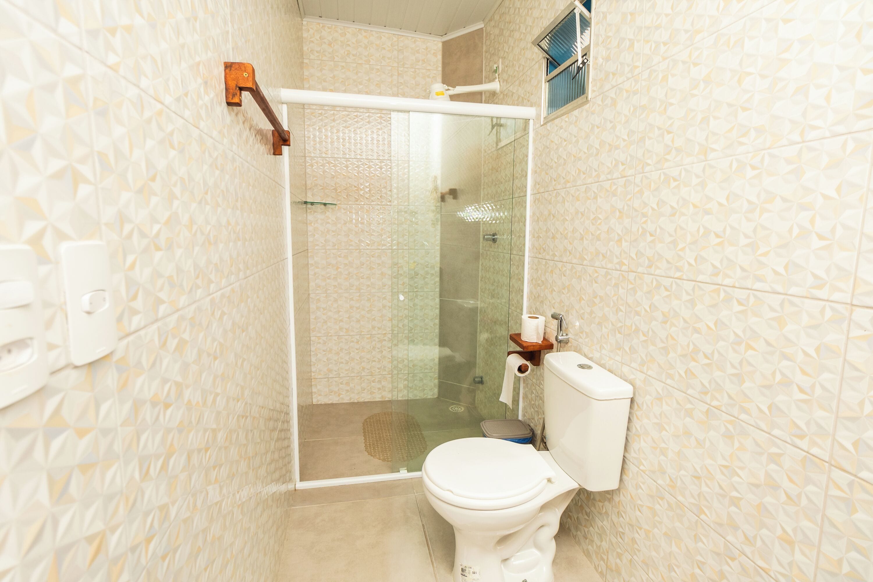 A bathroom with a glass-enclosed shower, a toilet, and a sink.