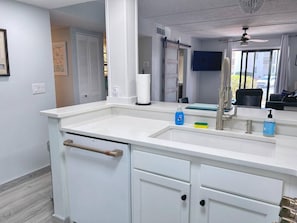 A modern kitchen with a white countertop, a double sink, and a built-in oven.