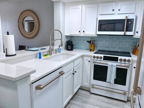 A modern kitchen with white cabinetry, a stainless steel range hood, and a built-in oven.