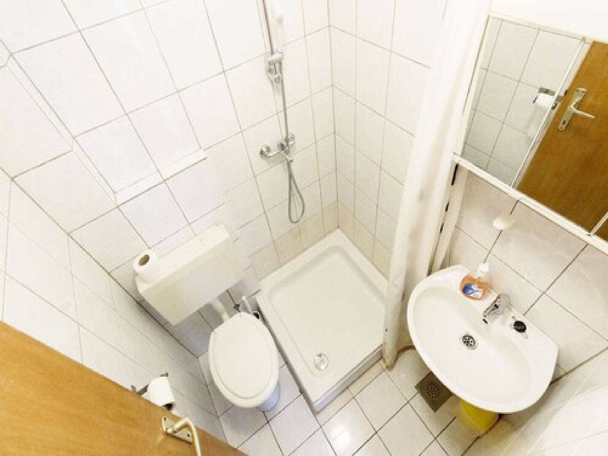 A small bathroom with a toilet, shower, and sink.