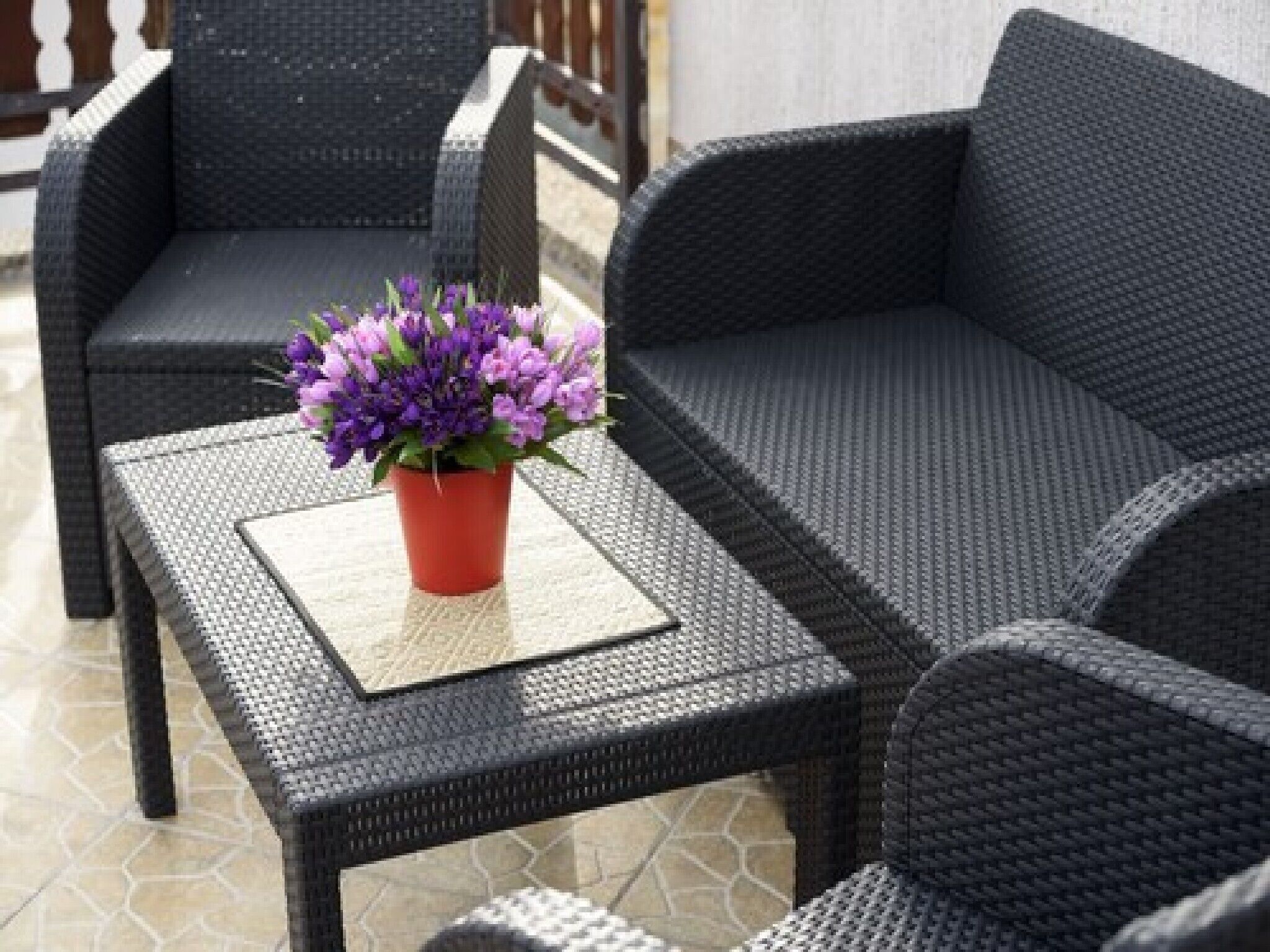 A patio area with wicker furniture, including a table with a potted plant.