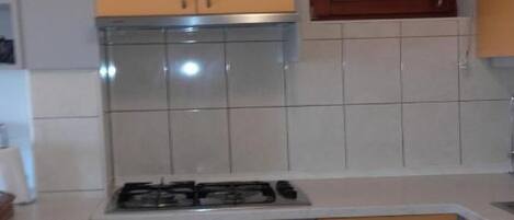 A compact kitchen with a gas stove, oven, and wooden cabinets.