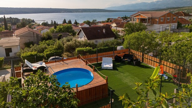 Un barrio residencial con piscina, patio cercado y casas con tejados rojos.