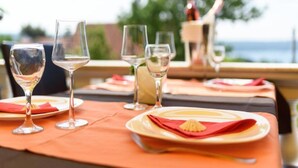 Una mesa dispuesta con copas de vino y platos, con vistas a un paisaje pintoresco.