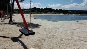 En strand med gynger og frit udsyn til havet.